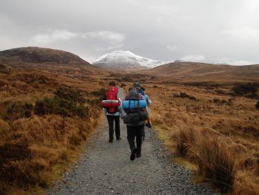 Three peole hiking, lonely mountain in background